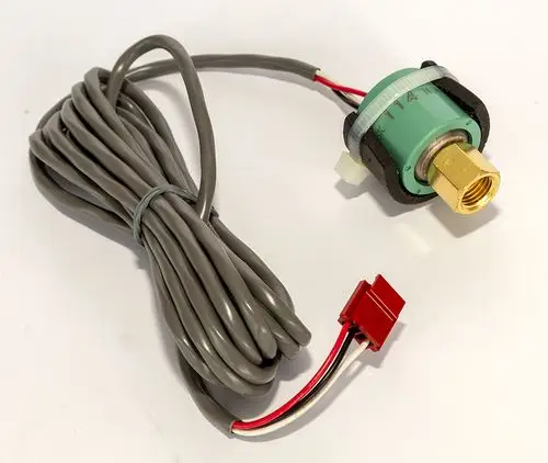 Drucksensor von Daikin mit grünem Gehäuse und goldener Anschlussschraube, umgeben von grauen Kabeln mit einem roten Stecker und zwei weiteren Leitungen.